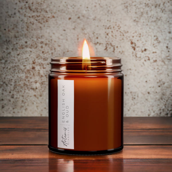 Artemis Candle Company Branded Soy Wax English Oak and Oud Scented Candle Shown In Amber Glass Jar